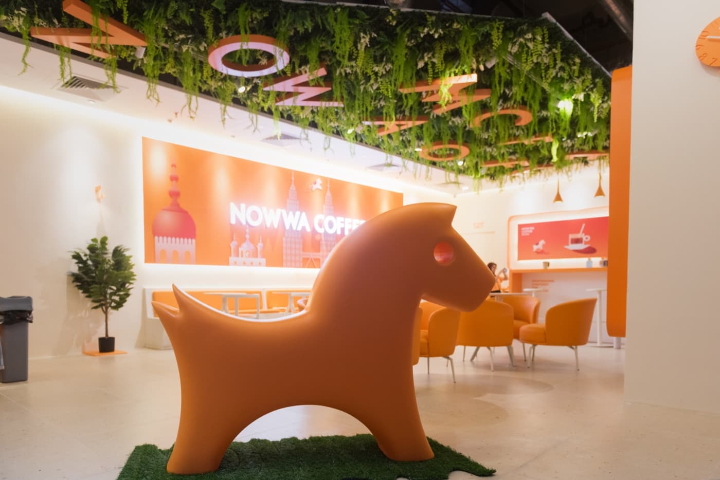 NOWWA Coffee store interior with the signature orange mascot