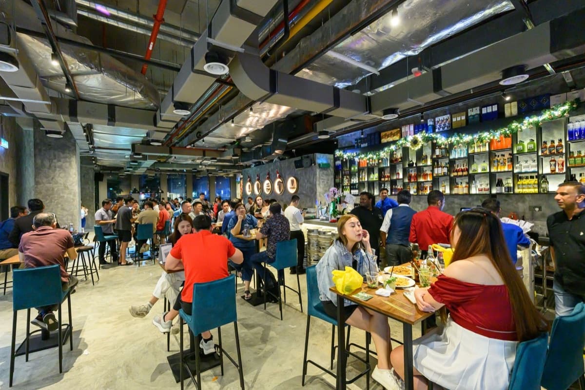 Guests unwinding over food and drinks at X Office Bar's lively interior